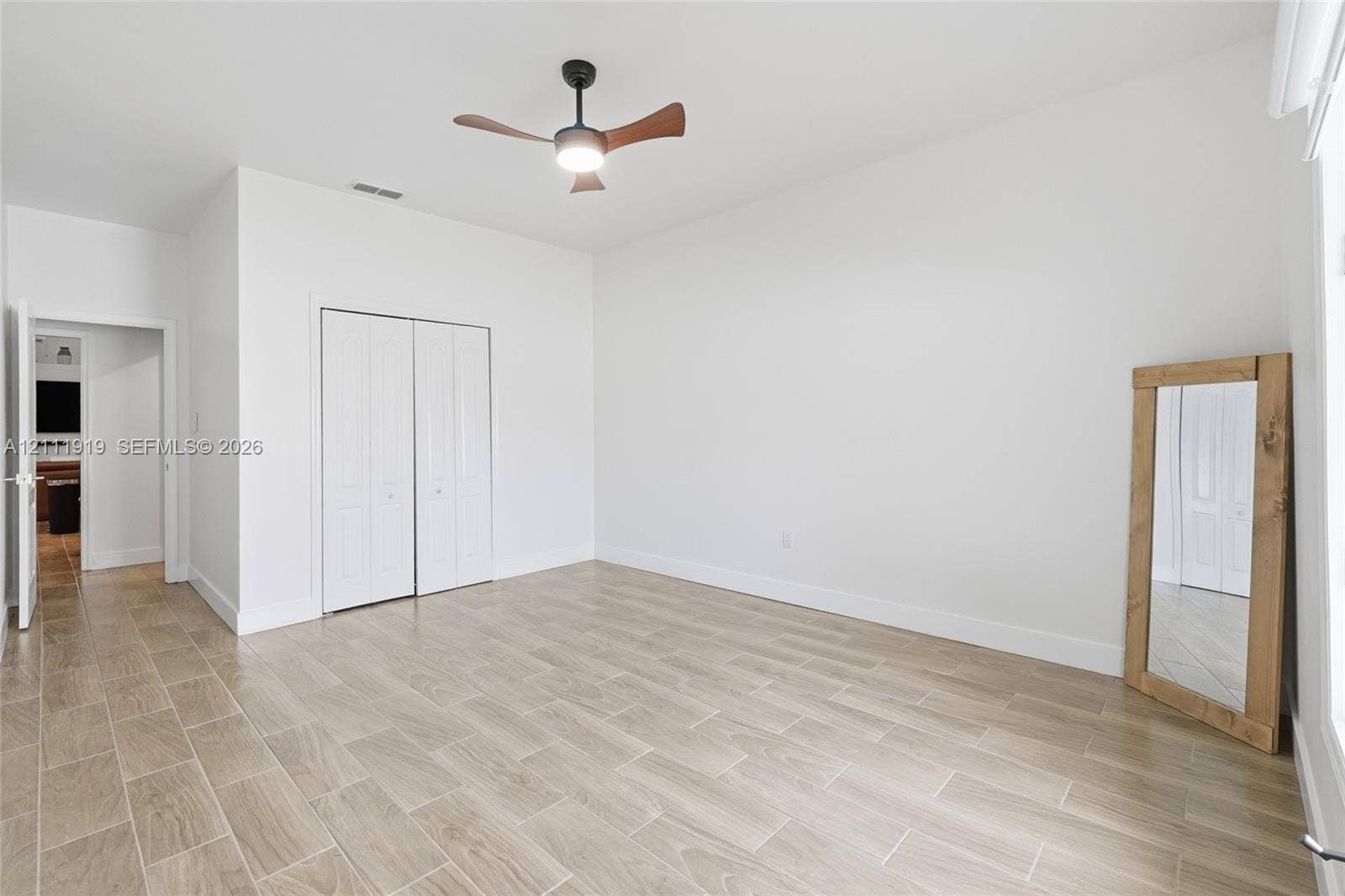 137 Arrowhead Lane, Haines City, FL 33844 Neutral interior space featuring wood-finish tile flooring, recessed LED ceiling fan with integrated lighting, and white bi-fold closet doors