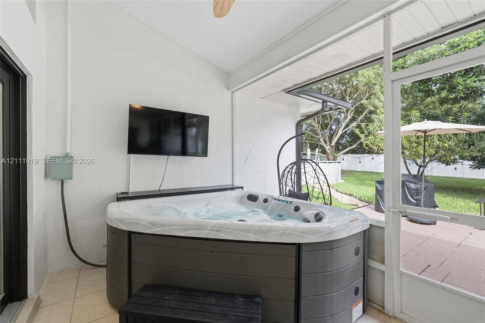 137 Arrowhead Lane, Haines City, FL 33844 Screened-in patio featuring tile flooring, ceiling fan, and built-in hot tub