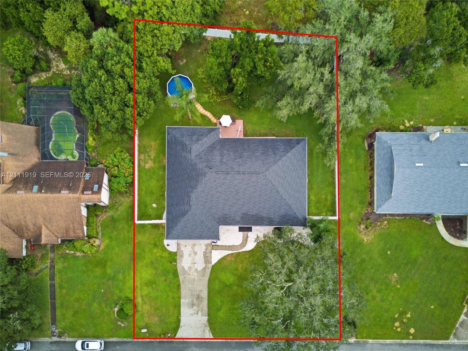 137 Arrowhead Lane, Haines City, FL 33844 Aerial perspective of a property featuring a multi-hipped roof, concrete driveway, rear deck, and mature landscaping
