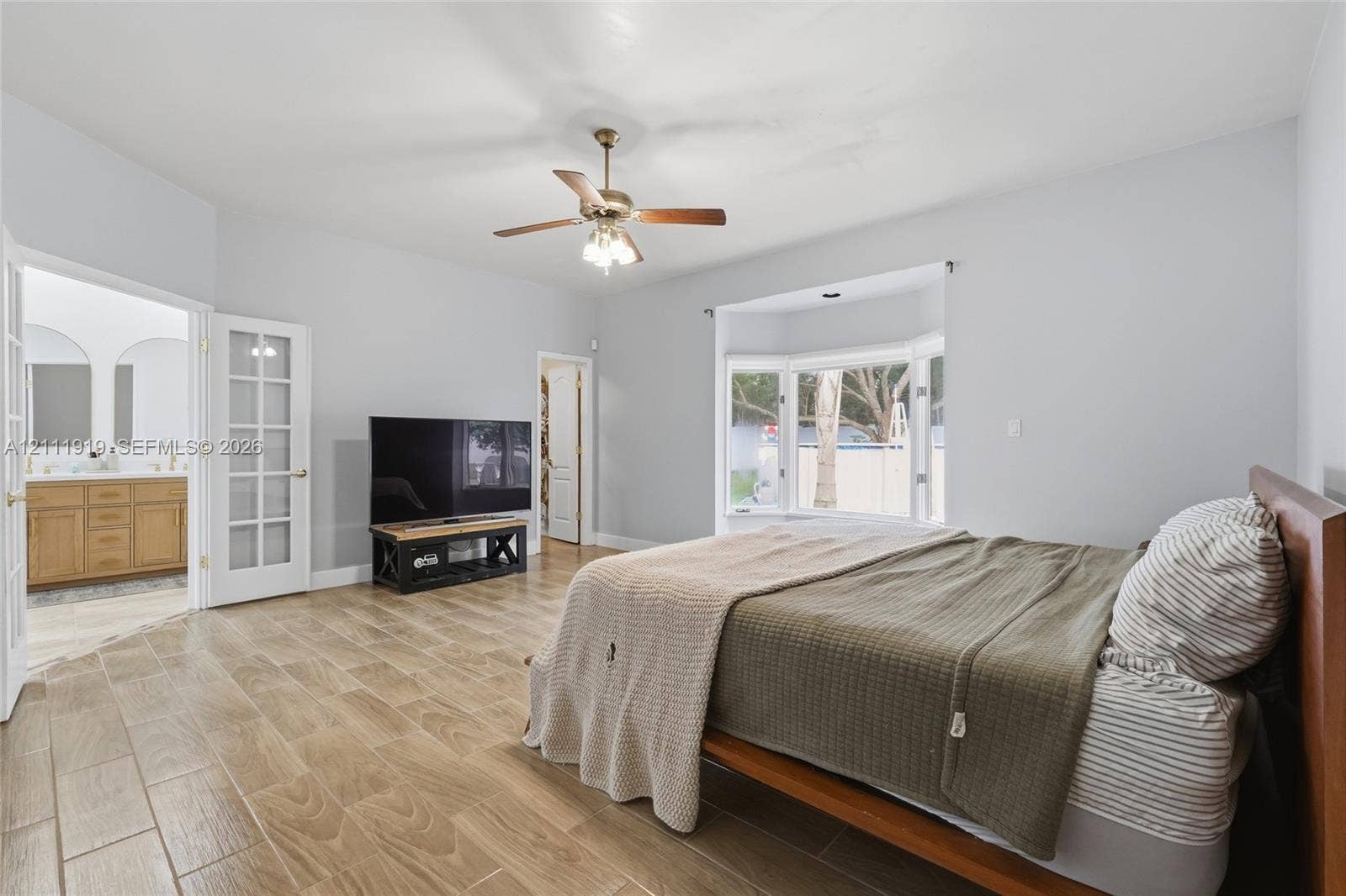 137 Arrowhead Lane, Haines City, FL 33844 Room featuring wood-finish tile flooring, a bay window, a ceiling fan with integrated lighting, and French doors