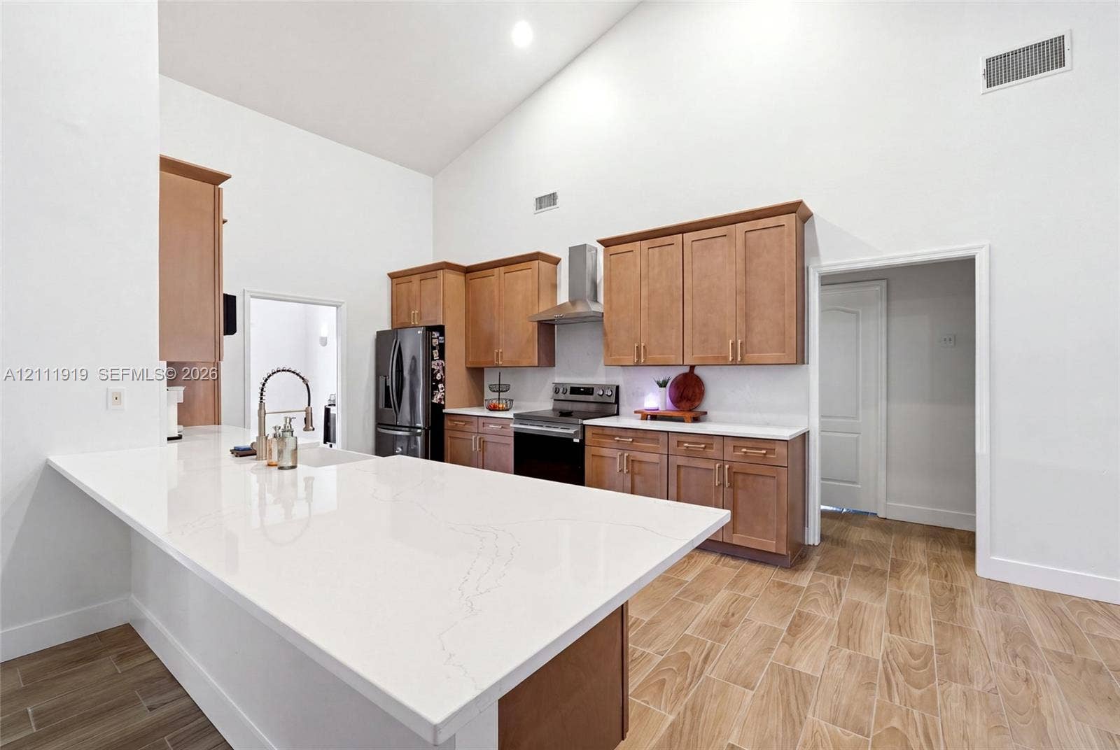 137 Arrowhead Lane, Haines City, FL 33844 Kitchen featuring vaulted ceilings, wood-finish flooring, quartz countertops, shaker-style wood cabinetry, and stainless steel appliances