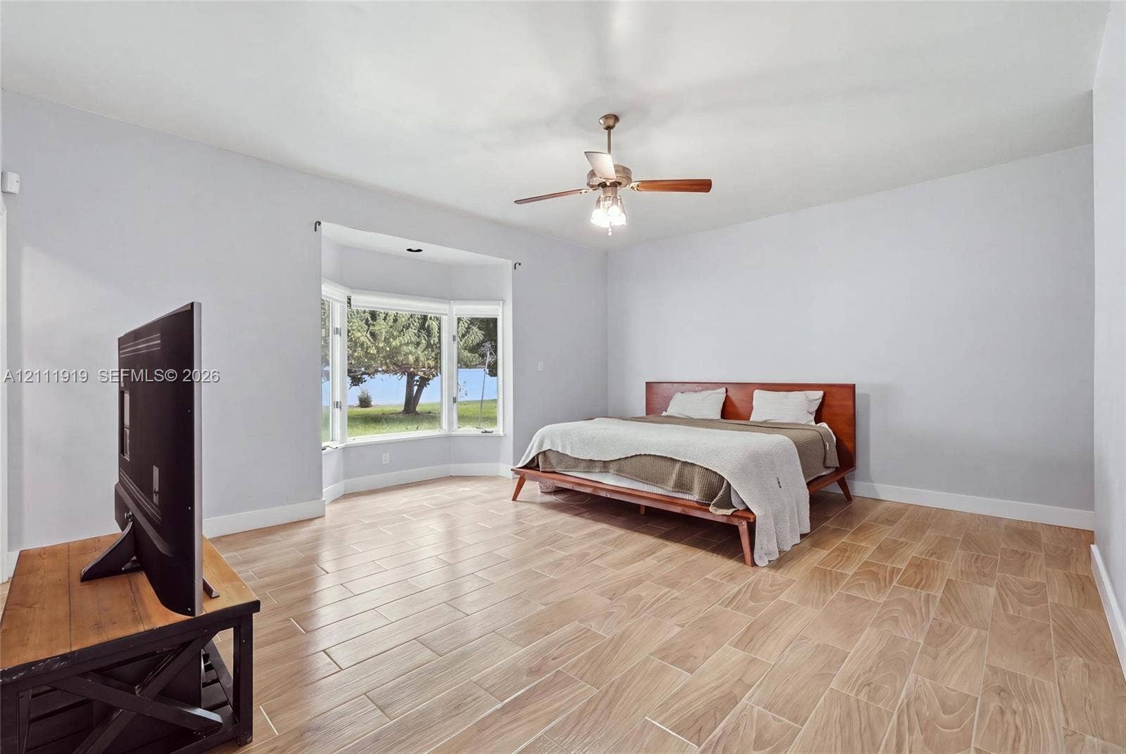 137 Arrowhead Lane, Haines City, FL 33844 Spacious room featuring wood-finish flooring, a prominent bay window, and a ceiling-mounted light fixture with a central fan