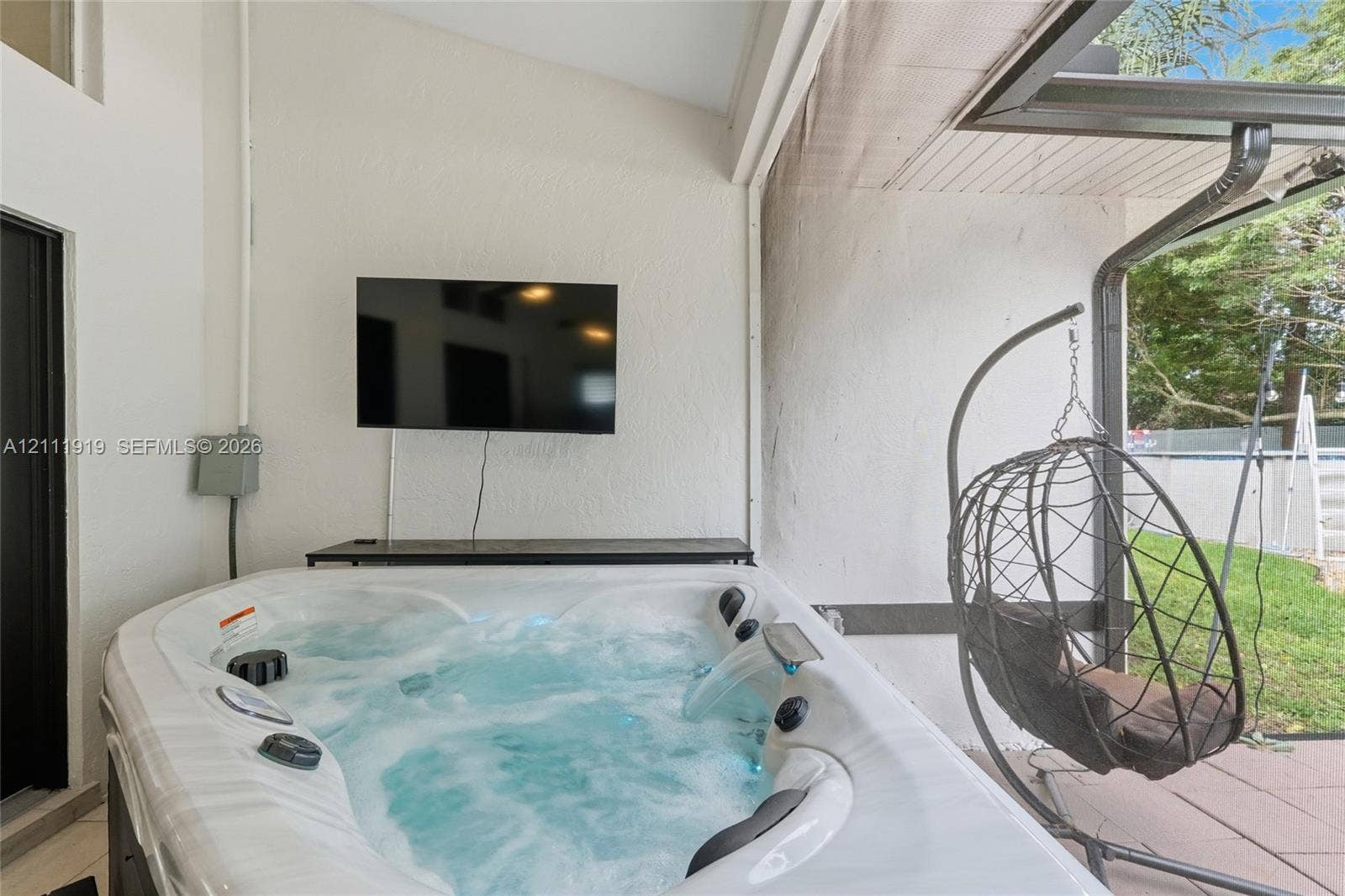 137 Arrowhead Lane, Haines City, FL 33844 Covered patio featuring an integrated hot tub with water feature, textured exterior walls, and tiled flooring