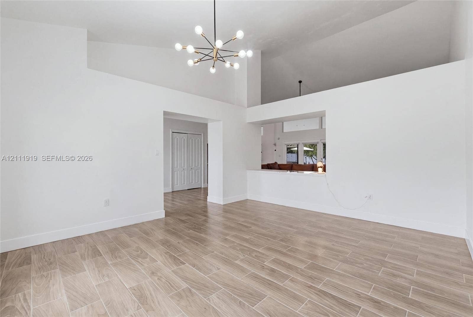 137 Arrowhead Lane, Haines City, FL 33844 High-volume room featuring a vaulted ceiling, wood-finish flooring, mid-century modern sputnik-style chandelier, and built-in architectural pass-through