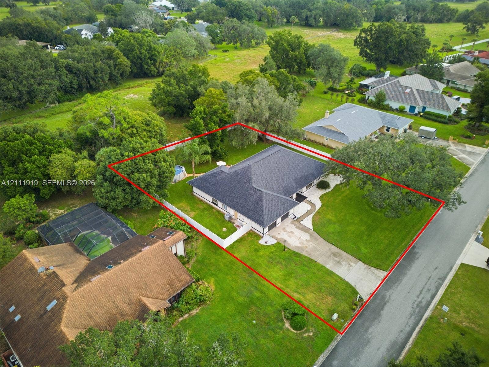 137 Arrowhead Lane, Haines City, FL 33844 Single-story residence featuring a hipped roof, attached multi-car garage, concrete driveway, and expansive lawn with mature trees