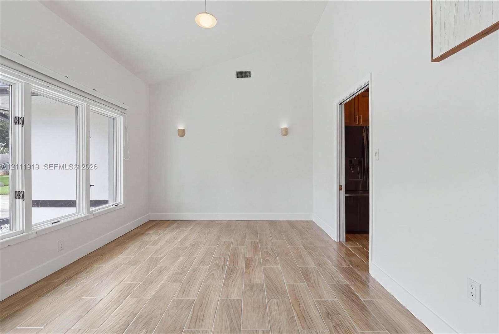 137 Arrowhead Lane, Haines City, FL 33844 Vaulted ceilings, wood-finish tile flooring, expansive windows, dual wall-mounted light fixtures, and a recessed ceiling light
