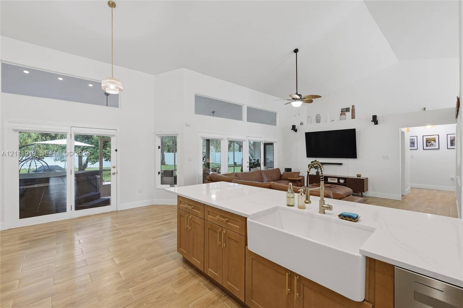137 Arrowhead Lane, Haines City, FL 33844 Open floor plan featuring vaulted ceilings, wood-finish flooring, a kitchen island with stone-surface countertop, white farmhouse sink, and transom windows