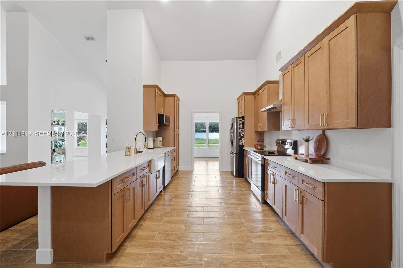 137 Arrowhead Lane, Haines City, FL 33844 Kitchen featuring vaulted ceilings, light-toned shaker cabinetry, quartz countertops, a farmhouse-style apron sink, and wood-finish tile flooring