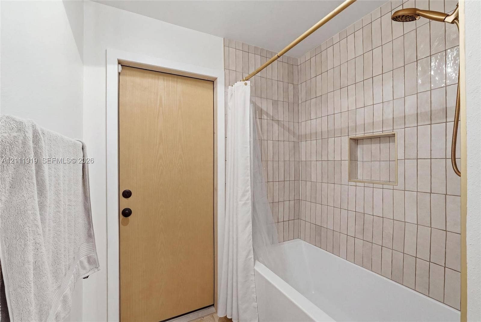 137 Arrowhead Lane, Haines City, FL 33844 Full bathroom featuring a tub-shower combination with floor-to-ceiling vertical ceramic wall tiles, a built-in recessed wall niche, and metallic hardware finish