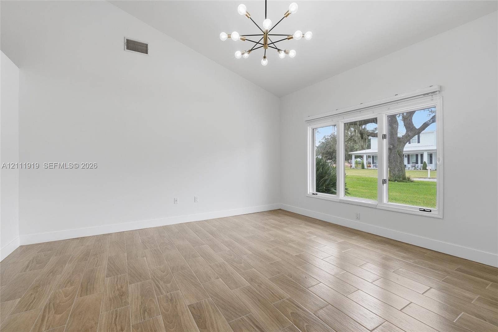 137 Arrowhead Lane, Haines City, FL 33844 Vaulted ceilings, wood-finish tile flooring, and a multi-light modern chandelier