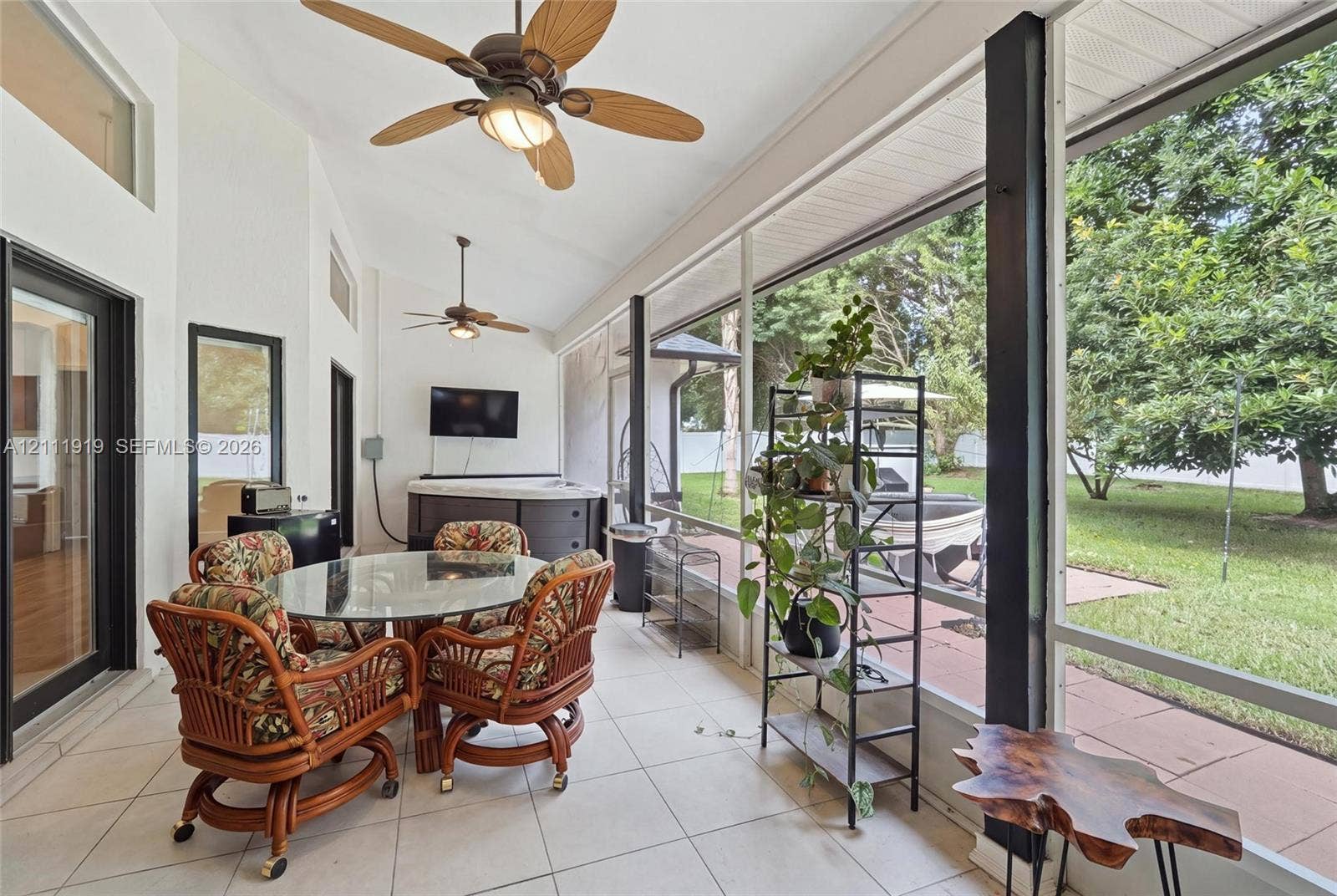 137 Arrowhead Lane, Haines City, FL 33844 Screened-in porch featuring vaulted ceilings, dual ceiling fans, tile flooring, and integrated wall-mounted exterior light fixtures
