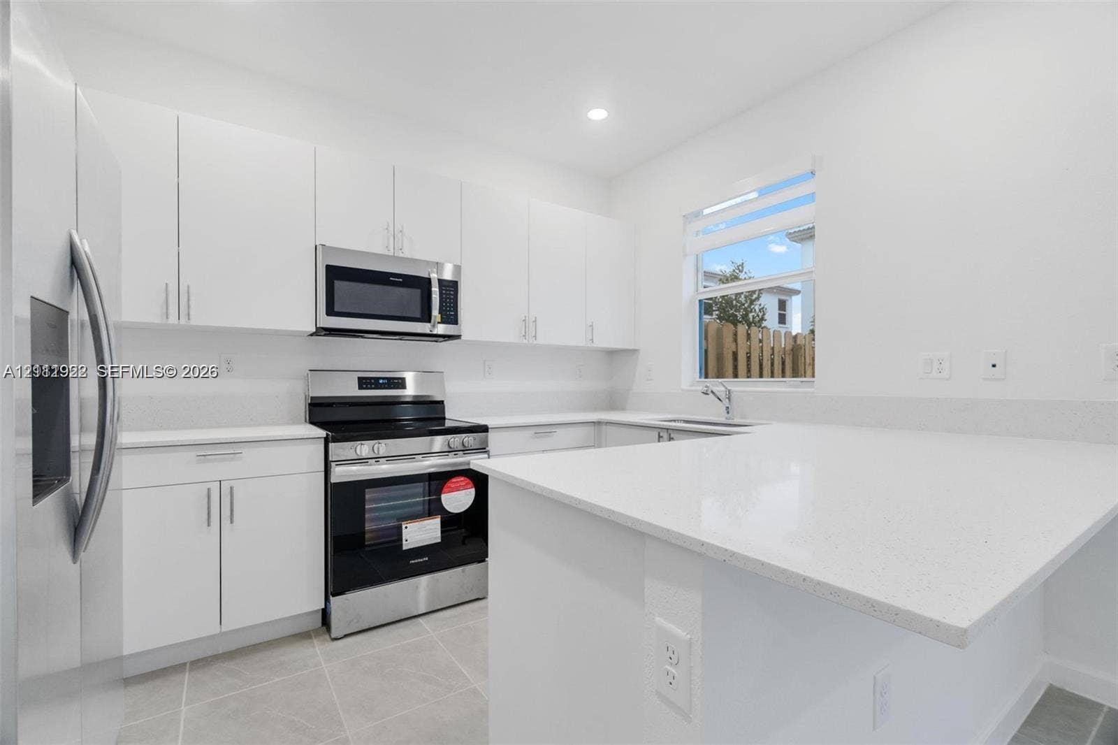 16281 SW 292nd Street, Homestead, FL 33033 Kitchen featuring white flat-panel cabinetry, quartz countertops, a peninsula breakfast bar, stainless steel appliances, and large-format tile flooring