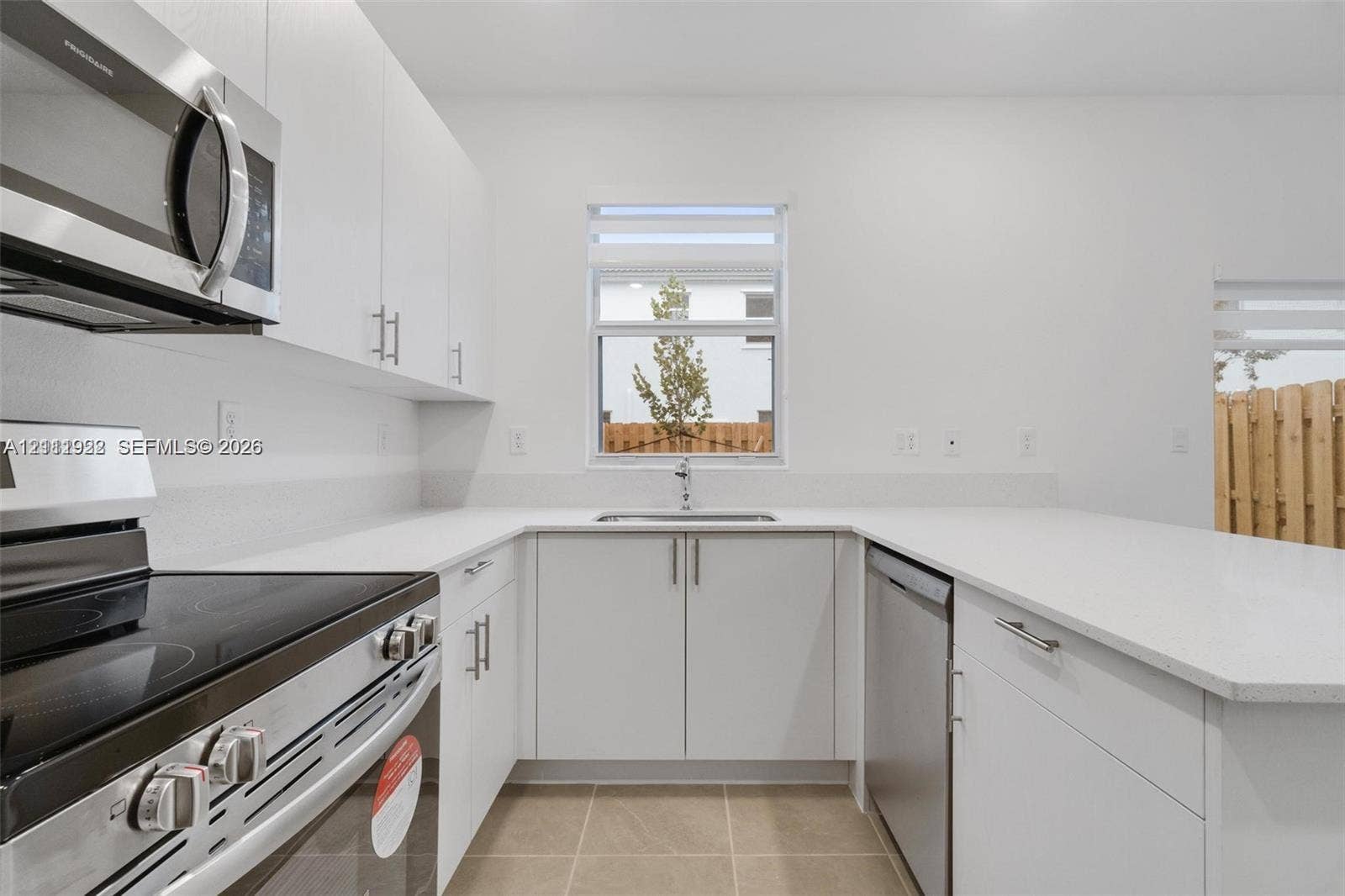 16281 SW 292nd Street, Homestead, FL 33033 Kitchen featuring flat-panel white cabinetry, stone-surface countertops, stainless steel appliances, and tile flooring