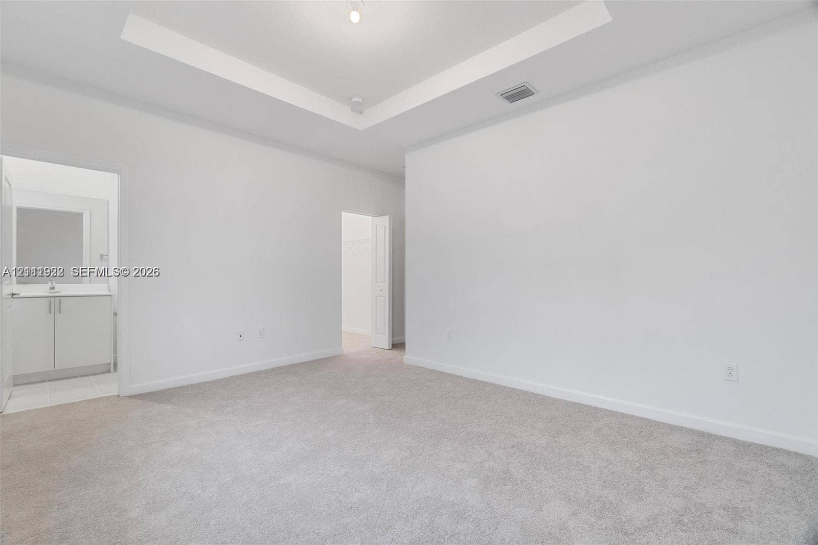 16281 SW 292nd Street, Homestead, FL 33033 Room featuring a tray ceiling, neutral wall-to-wall carpeting, and a built-in vanity with cabinetry