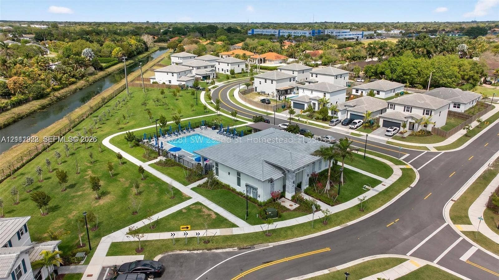 16281 SW 292nd Street, Homestead, FL 33033 Aerial perspective of a community featuring a swimming pool, paved pedestrian walkways, expansive green space, and a water canal