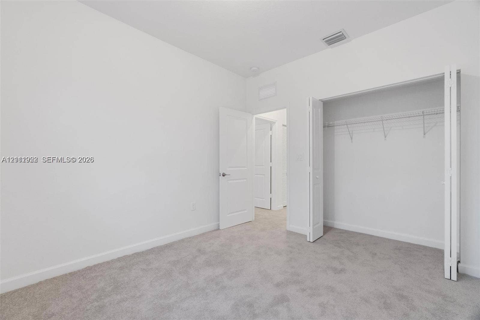 16281 SW 292nd Street, Homestead, FL 33033 Neutral interior space featuring wall-to-wall carpeting, white walls, multi-panel interior doors, and a closet with integrated wire shelving