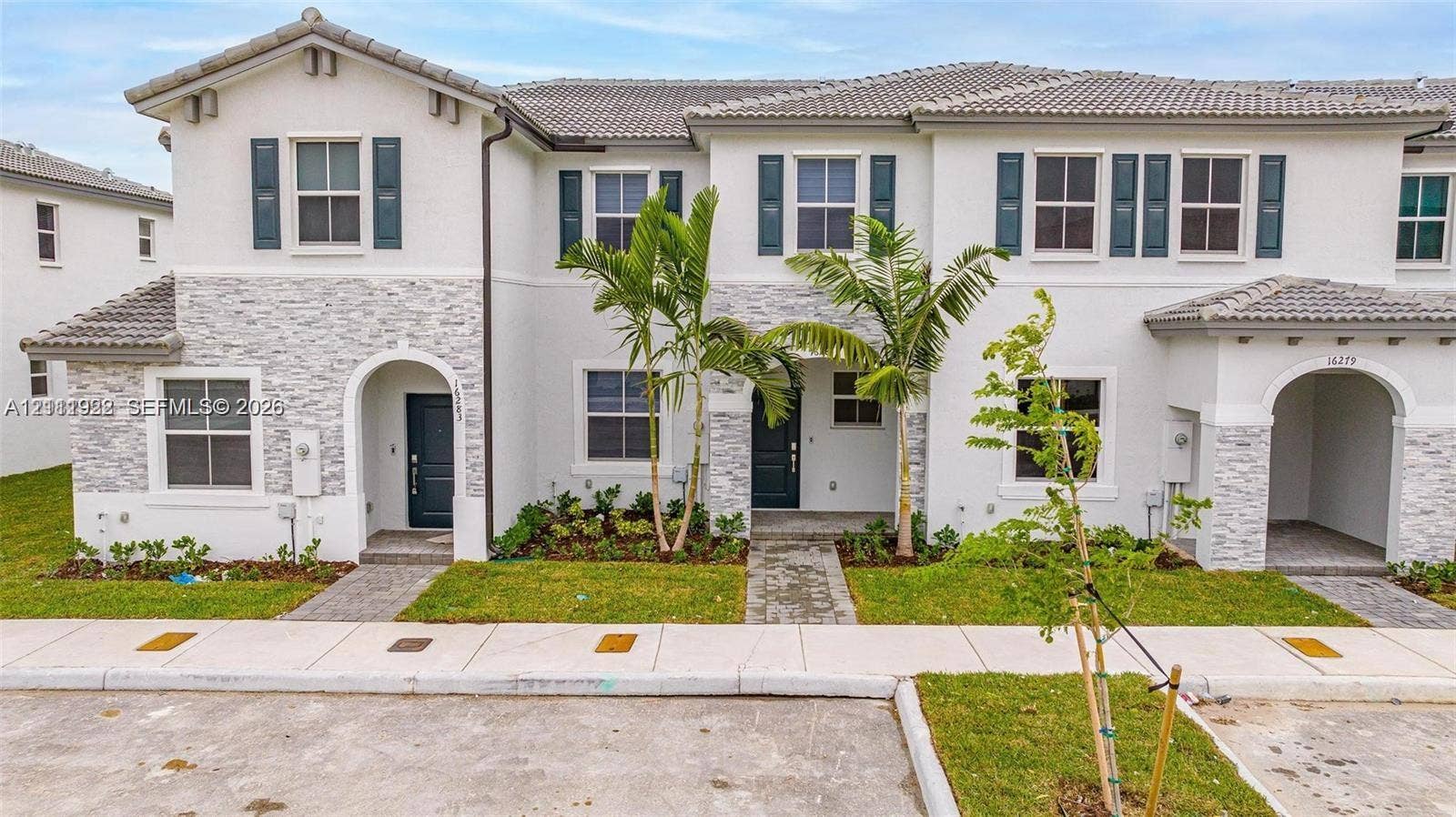 16281 SW 292nd Street, Homestead, FL 33033 Two-story exterior featuring a light-toned stucco finish, decorative stone veneer accents, multi-pane windows with dark shutters, and arched entryway detailing
