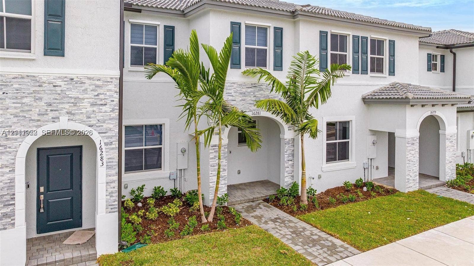 16281 SW 292nd Street, Homestead, FL 33033 Multi-story exterior featuring a light-toned stucco facade, stone veneer accents, arched entryways, and paver walkways
