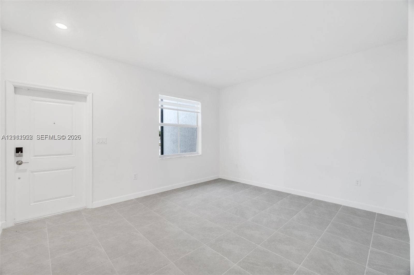 16281 SW 292nd Street, Homestead, FL 33033 Neutral-toned interior space featuring tile flooring, smooth white walls, recessed ceiling lighting, and a single-panel entry door with integrated electronic lock