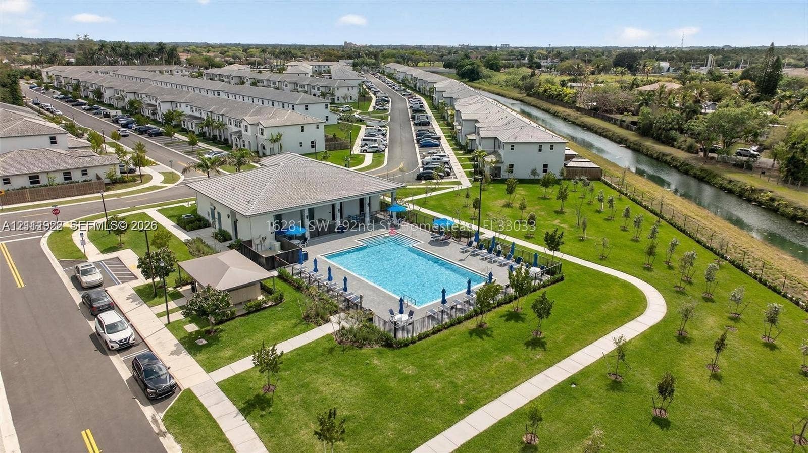 16281 SW 292nd Street, Homestead, FL 33033 Community swimming pool with a surrounding paved deck, covered pavilion structure, manicured green space, and concrete walking paths