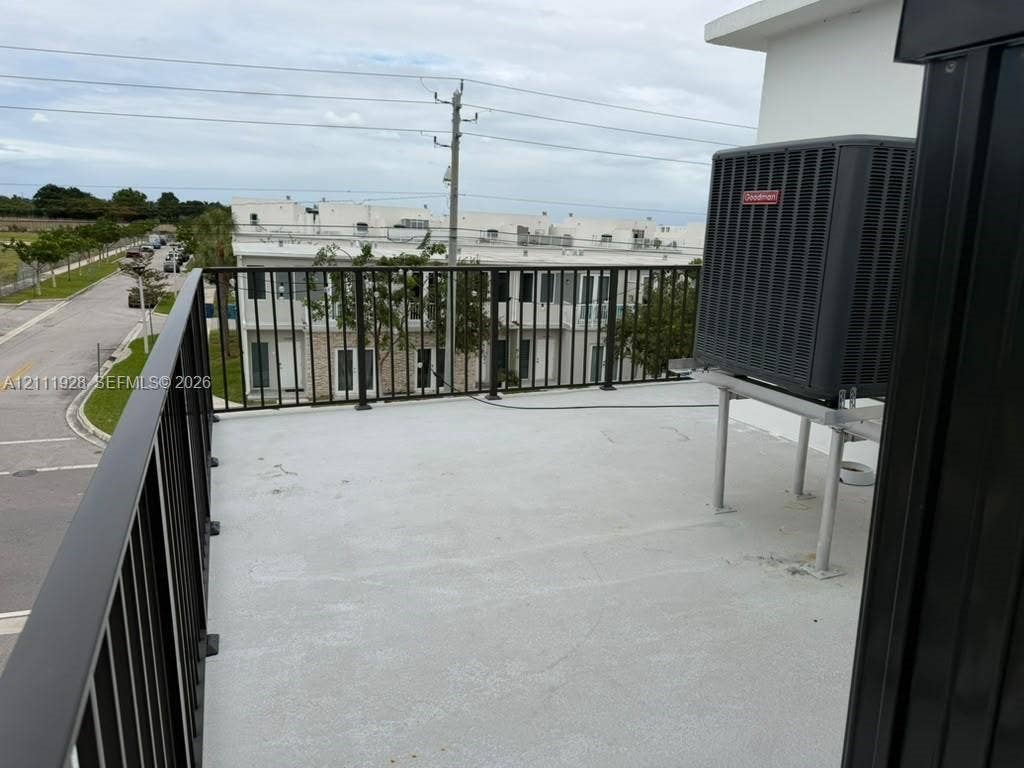 Elevated outdoor deck featuring a concrete surface, black metal railings, and a mounted HVAC unit