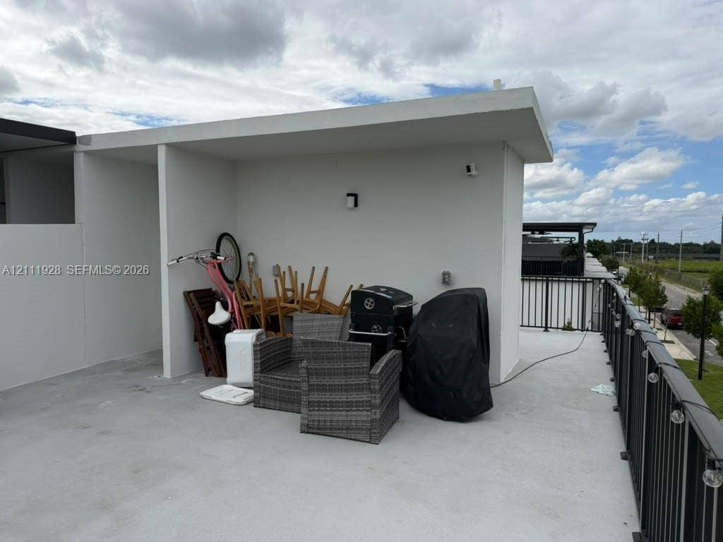 Rooftop terrace featuring concrete flooring, a sheltered alcove, and a dark metal railing with integrated string lighting