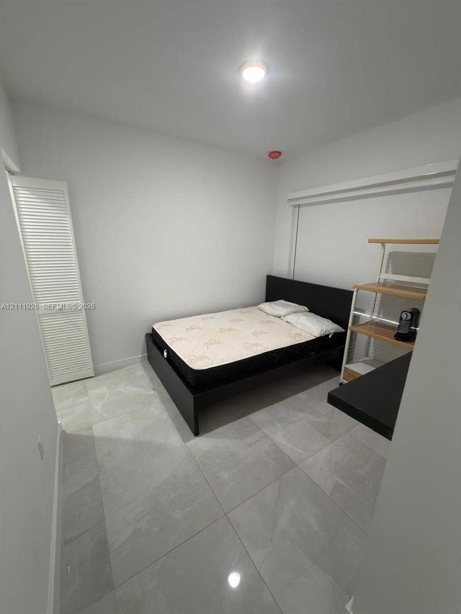 Neutral-toned, large-format tile flooring and a white louvered-door closet