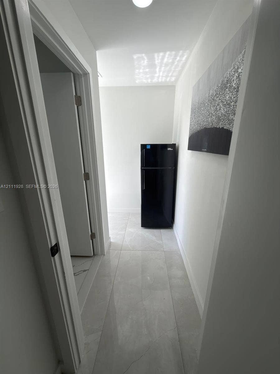 Large-format tile flooring, flush-mount ceiling lighting, and solid-core interior doors with matte black hardware