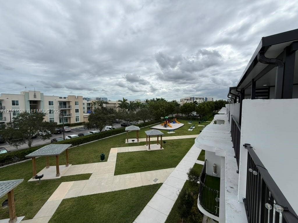 Communal green space featuring multiple covered pergolas, paved walkways, and integrated recreation area