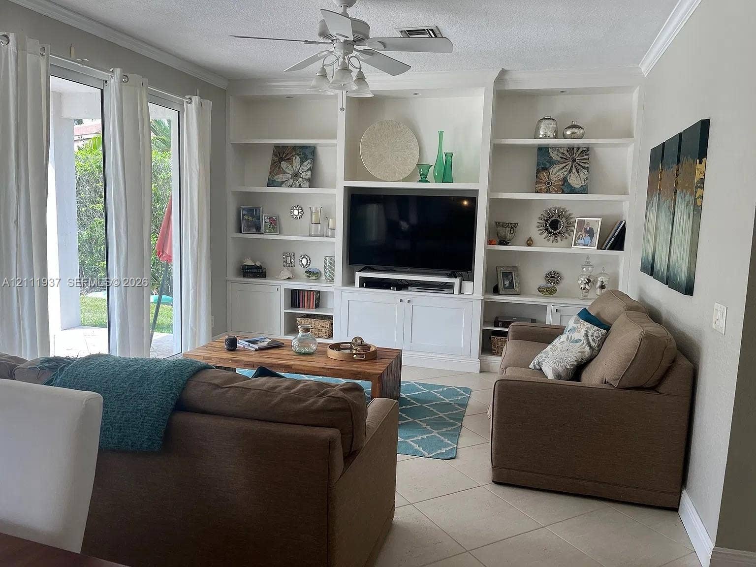 869 Nandina Drive, #869, Weston, Weston, FL 33327 Built-in white cabinetry featuring recessed shelving and lower closed storage, neutral tile flooring, crown molding, and sliding glass doors