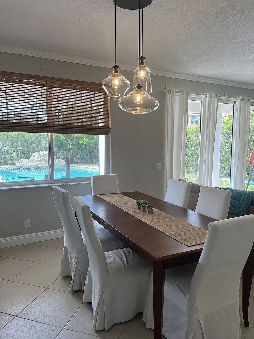 869 Nandina Drive, #869, Weston, Weston, FL 33327 Multi-light pendant fixture with clear glass shades, tile flooring, large windows, and sliding glass doors