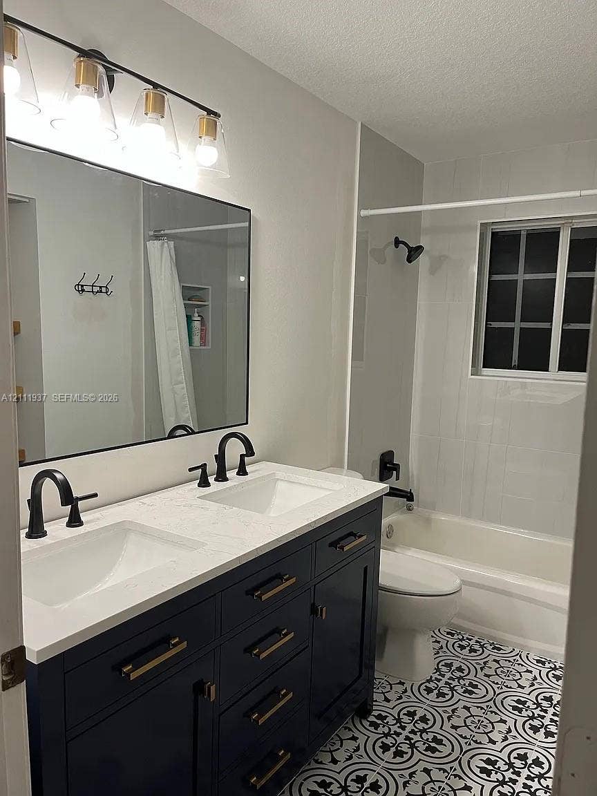 869 Nandina Drive, #869, Weston, Weston, FL 33327 Double vanity with a white countertop and dark blue cabinetry, featuring matte black hardware, a geometric-patterned tile floor, and a four-light vanity fixture