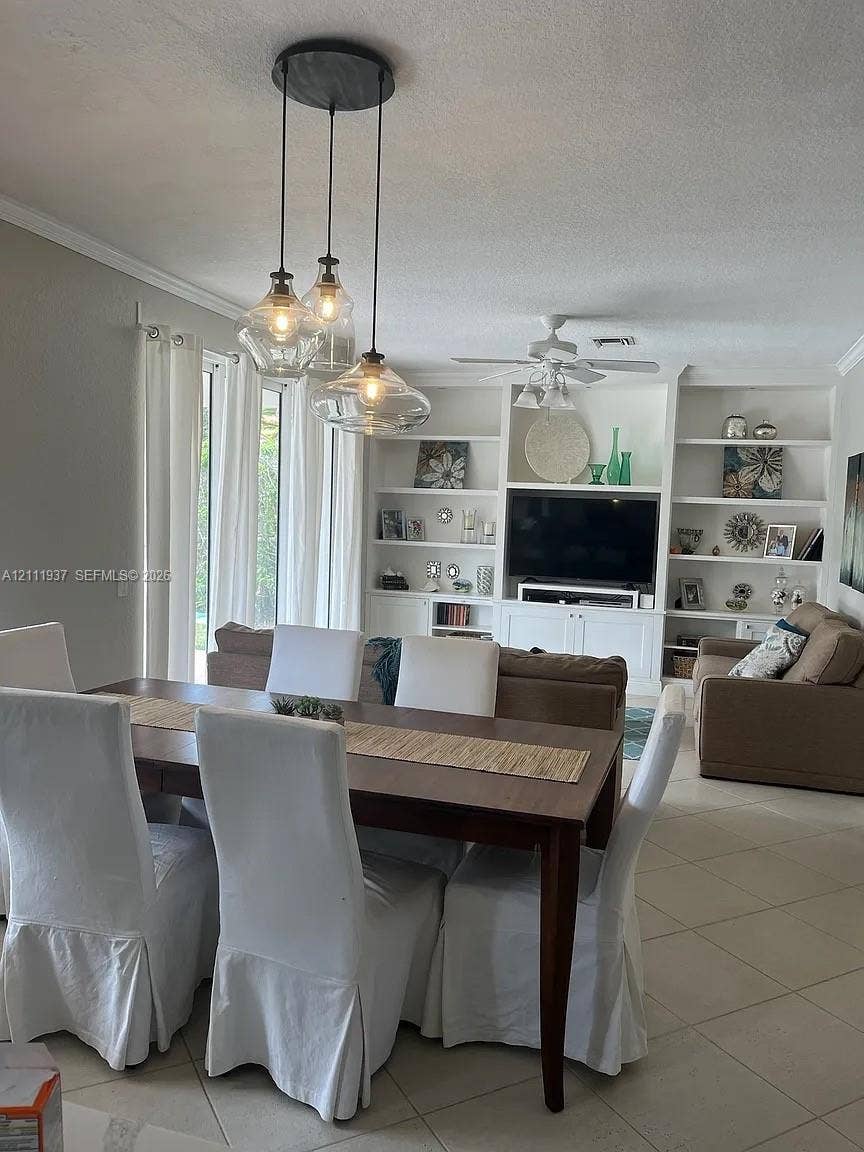 869 Nandina Drive, #869, Weston, Weston, FL 33327 Built-in floor-to-ceiling shelving and cabinetry, three-light glass pendant fixture, neutral tile flooring, and ceiling fan