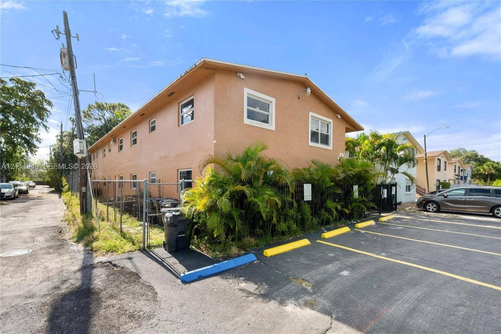Multi-unit exterior featuring stucco siding, double-hung windows, and asphalt-paved surface parking