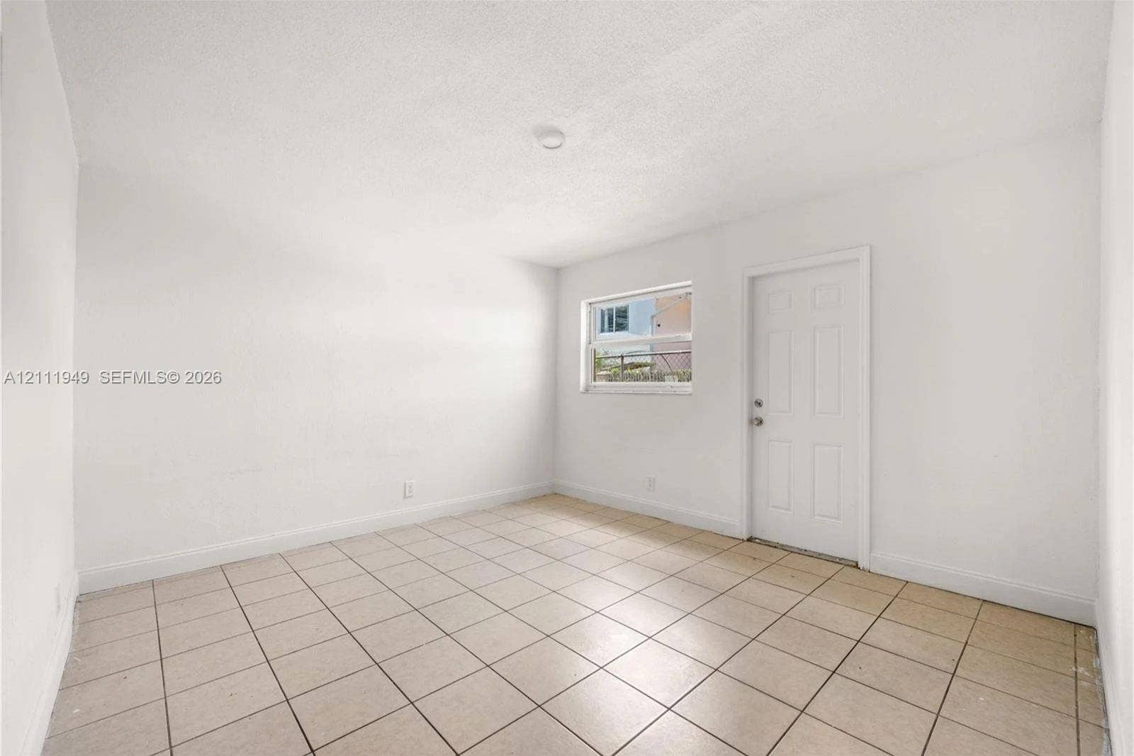 Interior space featuring neutral wall finishes, large-format ceramic floor tile, and a six-panel exterior door