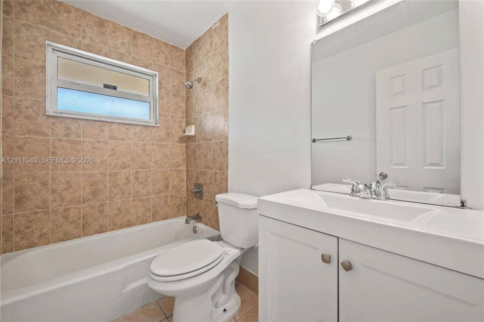 Bathroom featuring a vanity with white cabinetry, a single-basin sink, and a full-width wall mirror