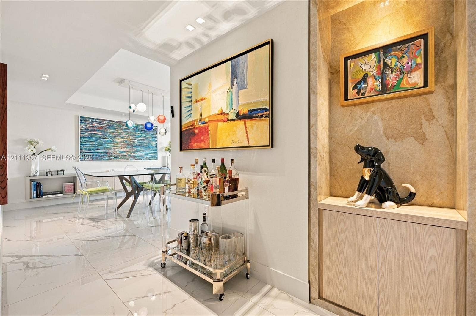 Interior featuring recessed stone-clad display alcove with built-in cabinetry, polished tile flooring with marble-style veining, recessed ceiling lighting, and suspended multi-globe light fixture