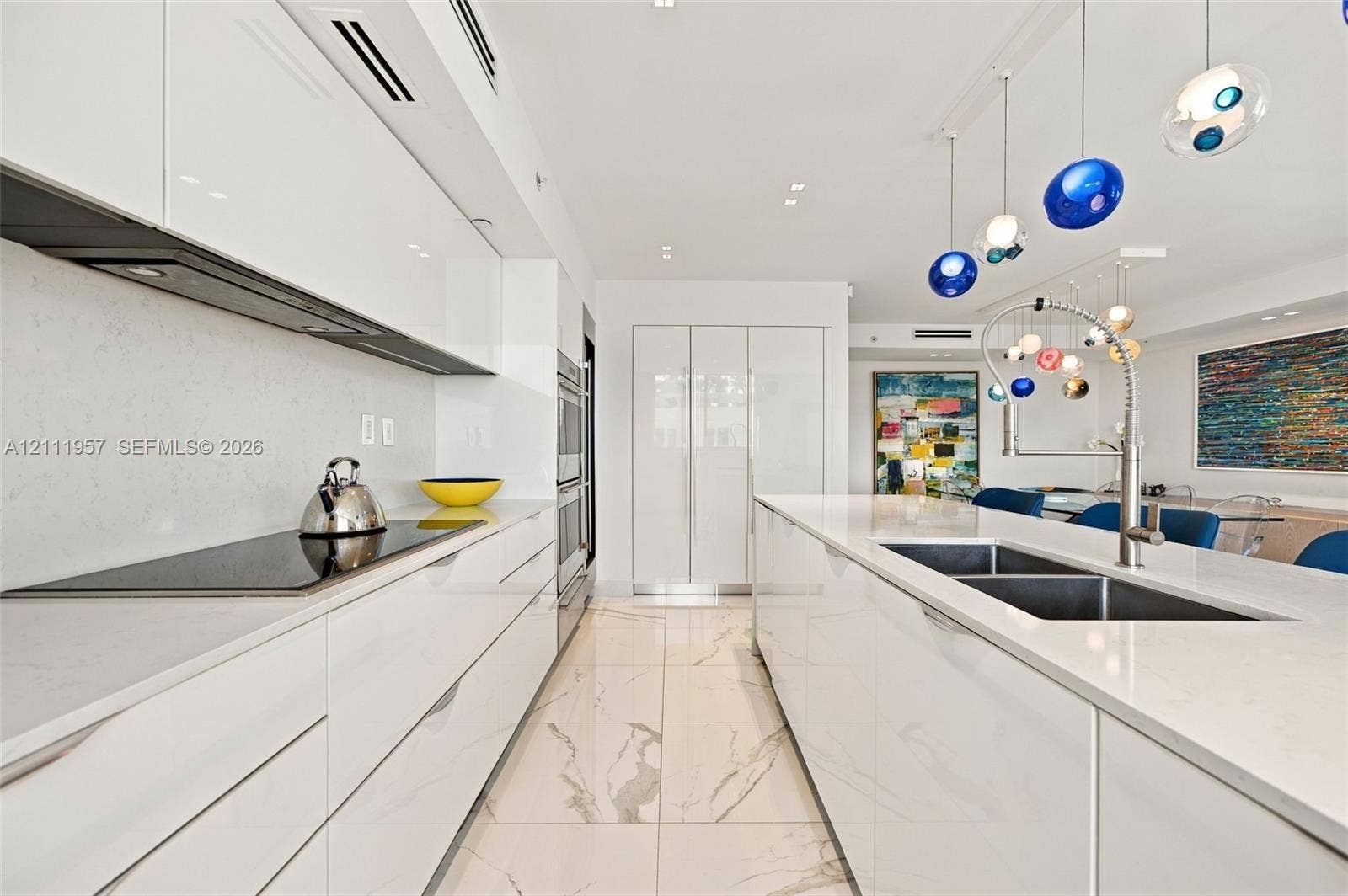 Contemporary kitchen featuring high-gloss cabinetry, quartz countertops, large-format veined tile flooring, a stainless steel double-basin sink with pull-down faucet, and built-in stainless steel double wall ovens