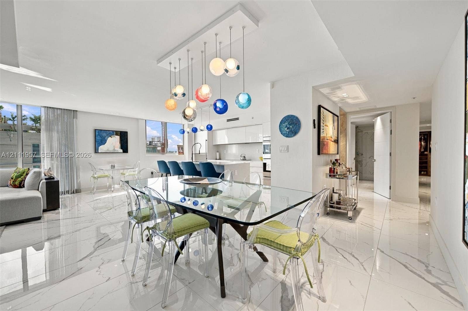 Large format tile flooring with high-gloss finish, multi-colored tiered glass globe chandelier, expansive floor-to-ceiling windows, and minimalist kitchen cabinetry