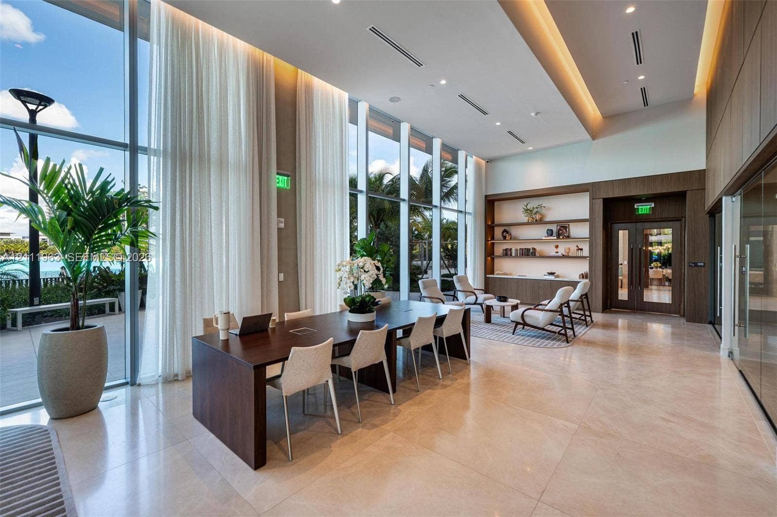 Expansive common area featuring floor-to-ceiling glass walls, integrated wood-paneled wall accents, recessed architectural lighting, and polished stone flooring