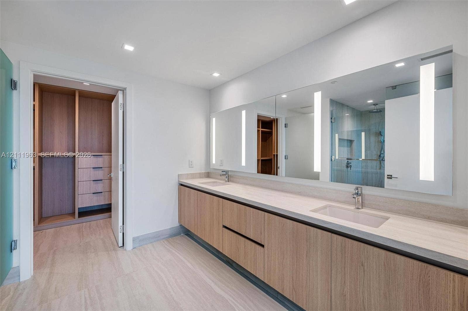 Custom floor-to-ceiling built-in cabinetry featuring light wood-finish shelving, multiple integrated hanging rods, and drawers with matte black pulls