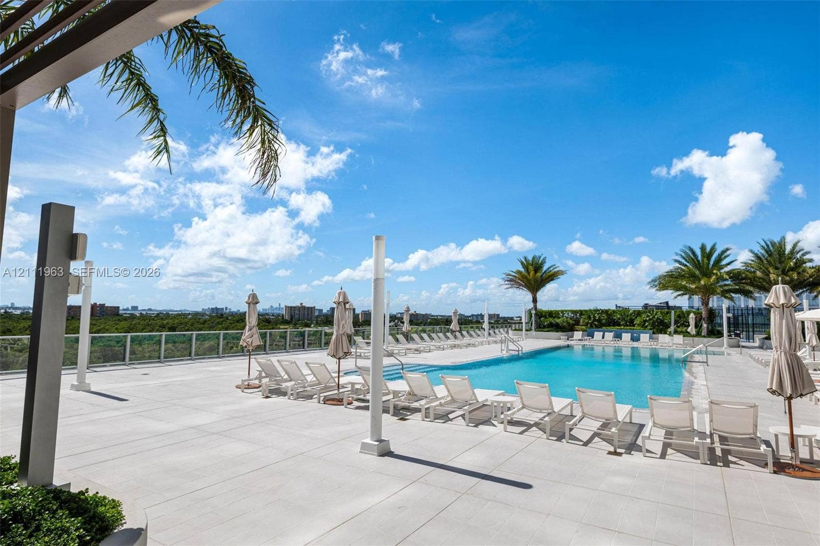 In-ground swimming pool featuring a mosaic tile water feature with four integrated spillways, stone-style pool decking, and a stainless steel entry rail