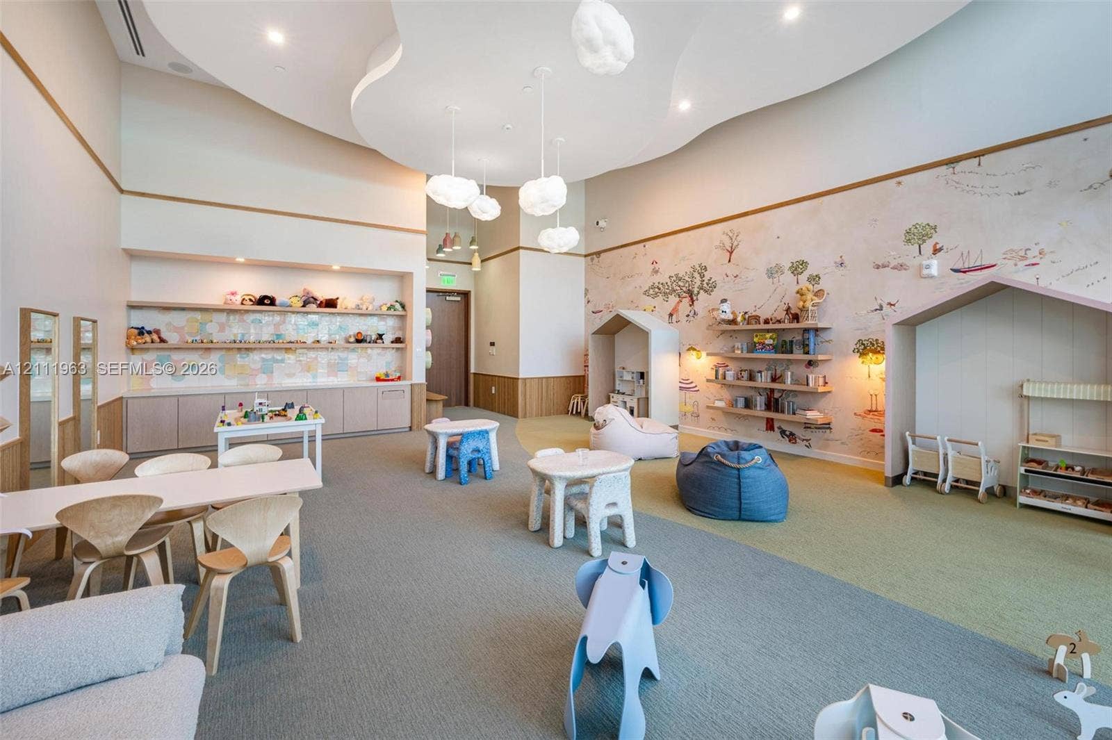Floor-to-ceiling glass windows, wood-finish flooring, recessed tray ceiling with integrated lighting, custom built-in media wall with inset display, and sculptural multi-bulb pendant lighting