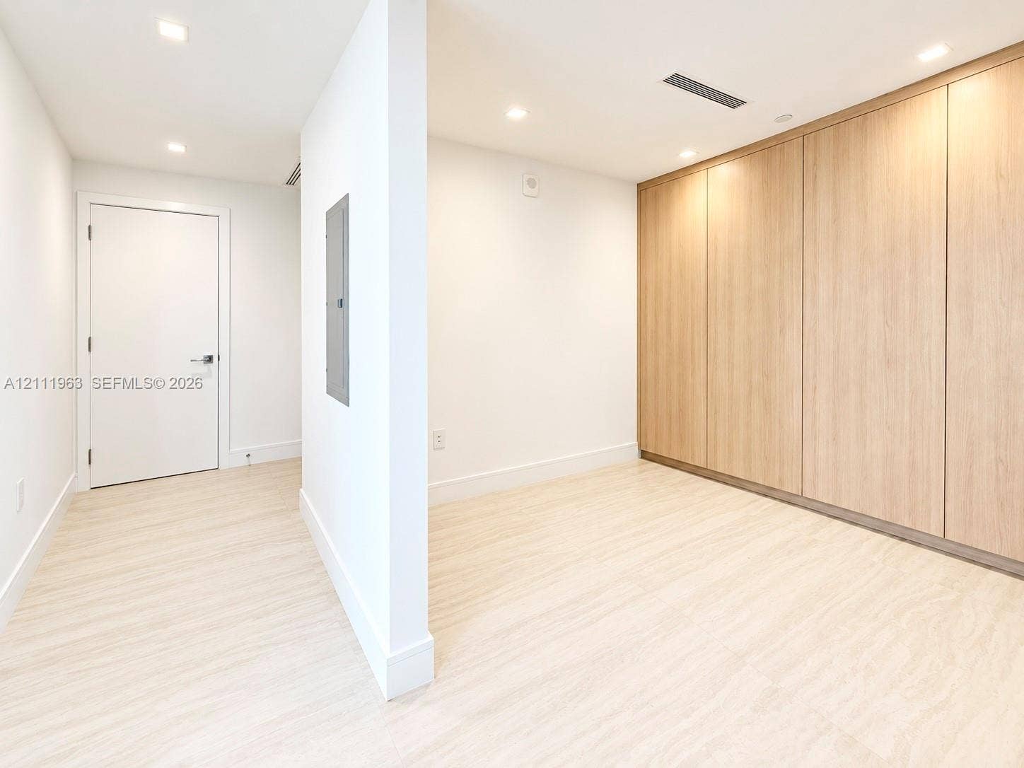 Custom built-in closet featuring light wood-finish cabinetry, adjustable shelving, integrated drawer storage, and recessed ceiling lighting
