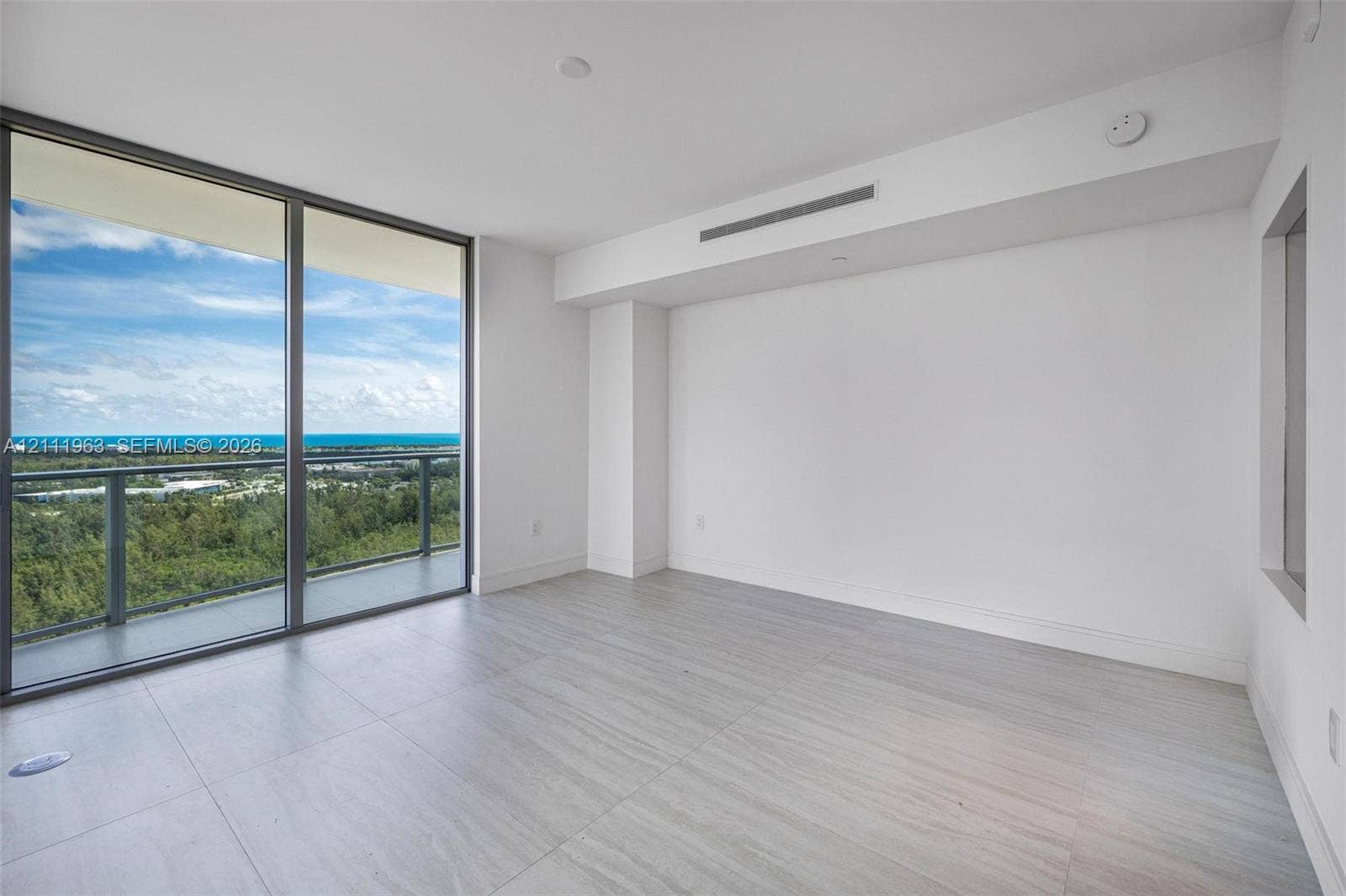 Neutral interior space featuring recessed linear ceiling diffusers, light-toned wood-finish flooring, a built-in recessed wall niche, and minimalist solid-core doors