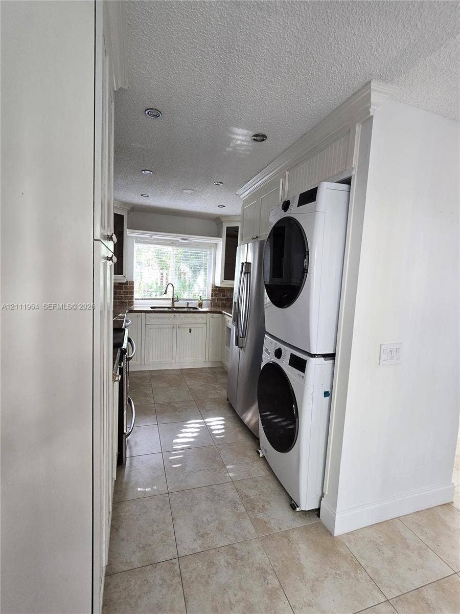 Kitchen featuring white beadboard cabinetry, recessed ceiling lighting, tile flooring, and integrated laundry appliances