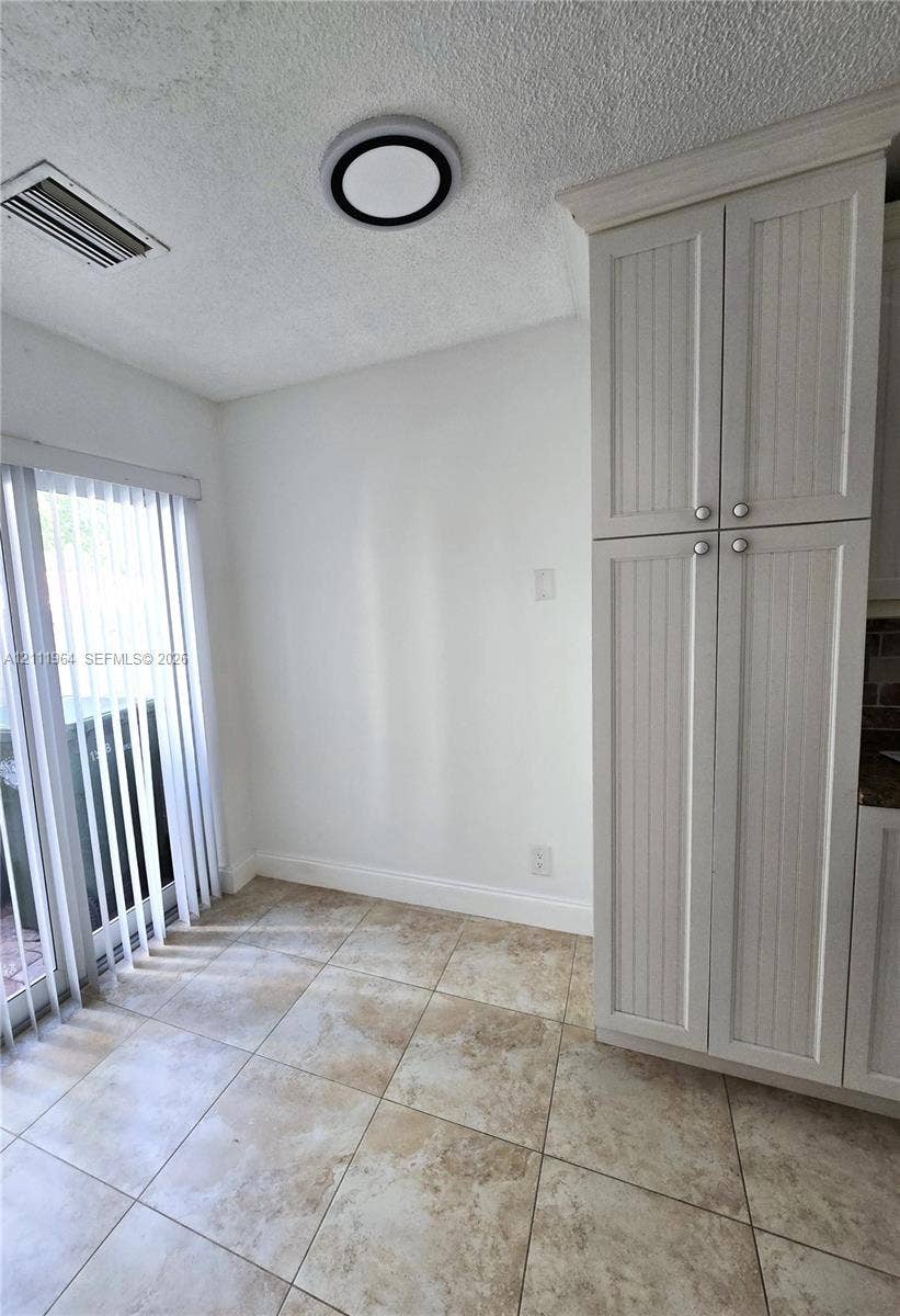 Tall white beadboard-style cabinetry, square stone-finish floor tiling, and a recessed ceiling light fixture