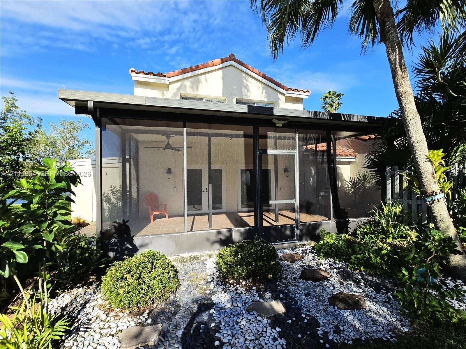 Screen-enclosed patio with a hardscape stone garden and palm trees
