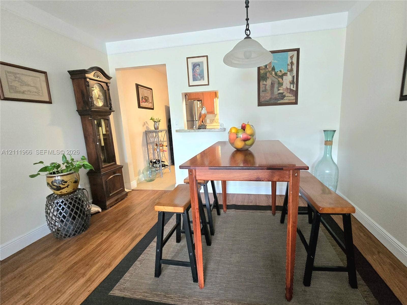 5387 SW 40th Avenue, #203, Dania Beach, FL 33314 Wood-finish flooring, neutral wall tones, pendant lighting fixture, and a pass-through wall cutout