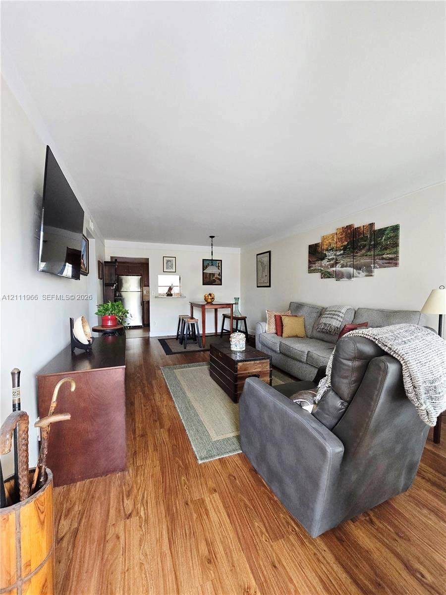 5387 SW 40th Avenue, #203, Dania Beach, FL 33314 Open-concept interior featuring wood-finish flooring, a wall-mounted television, neutral paint, and an overhead pendant light fixture